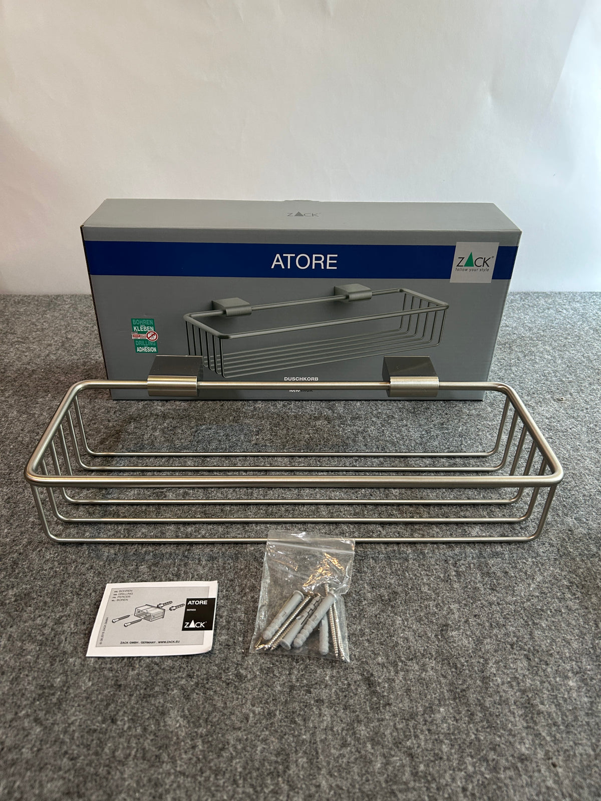 ZACK 40426Y:ATOREのシャワーバスケット:バスケットの枠と底面、袋入りの取付部品と説明書が見える全体像
