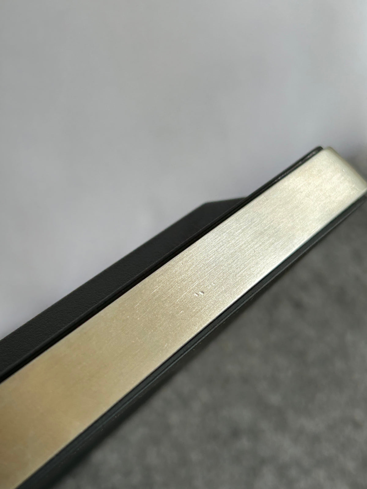ZACK 60050Y：HOYOの壁掛け時計：金属色の側枠の表面と黒い前面の縁が見える拡大
