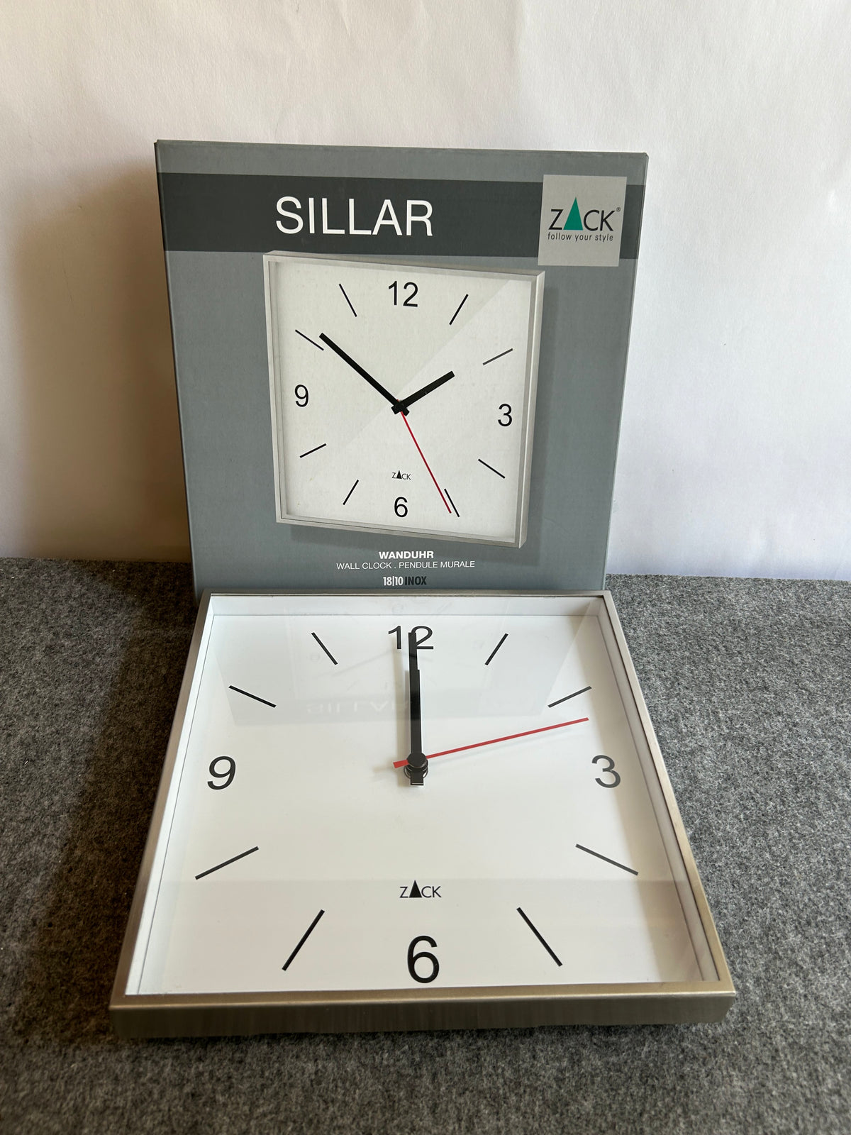 ZACK 60053Y：SILLARの壁掛け時計：白い文字盤の角形の時計を製品の箱の前に置いた全体像